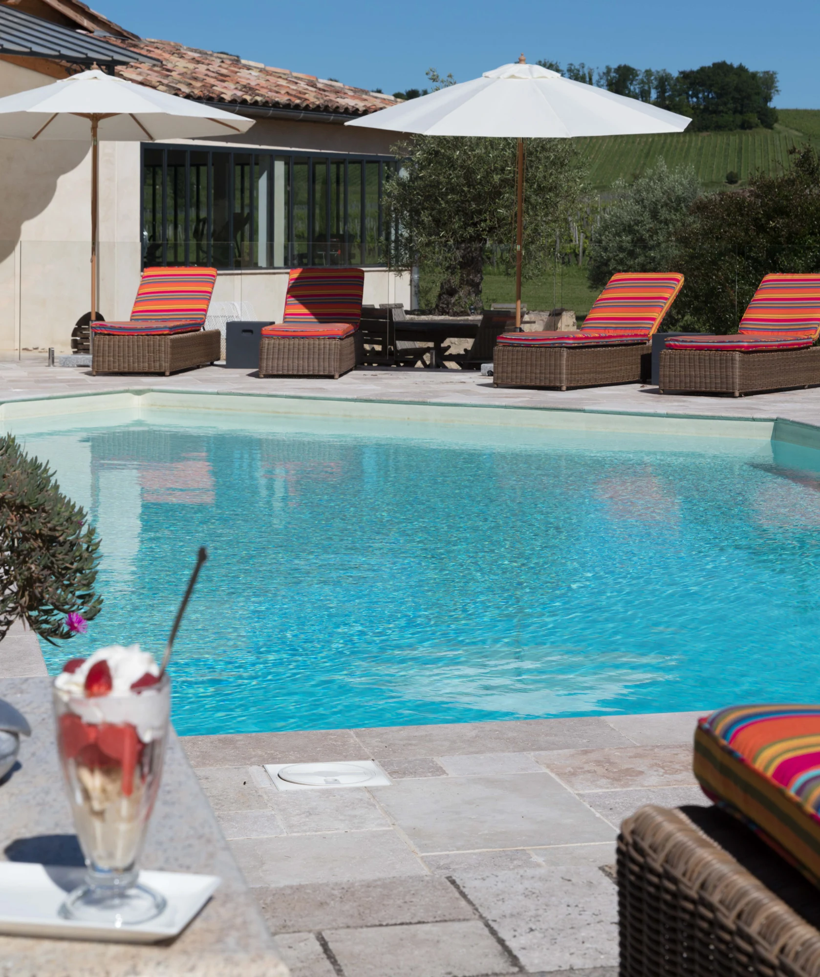 Cocktail au premier plan devant la piscine extérieure du Palanquey