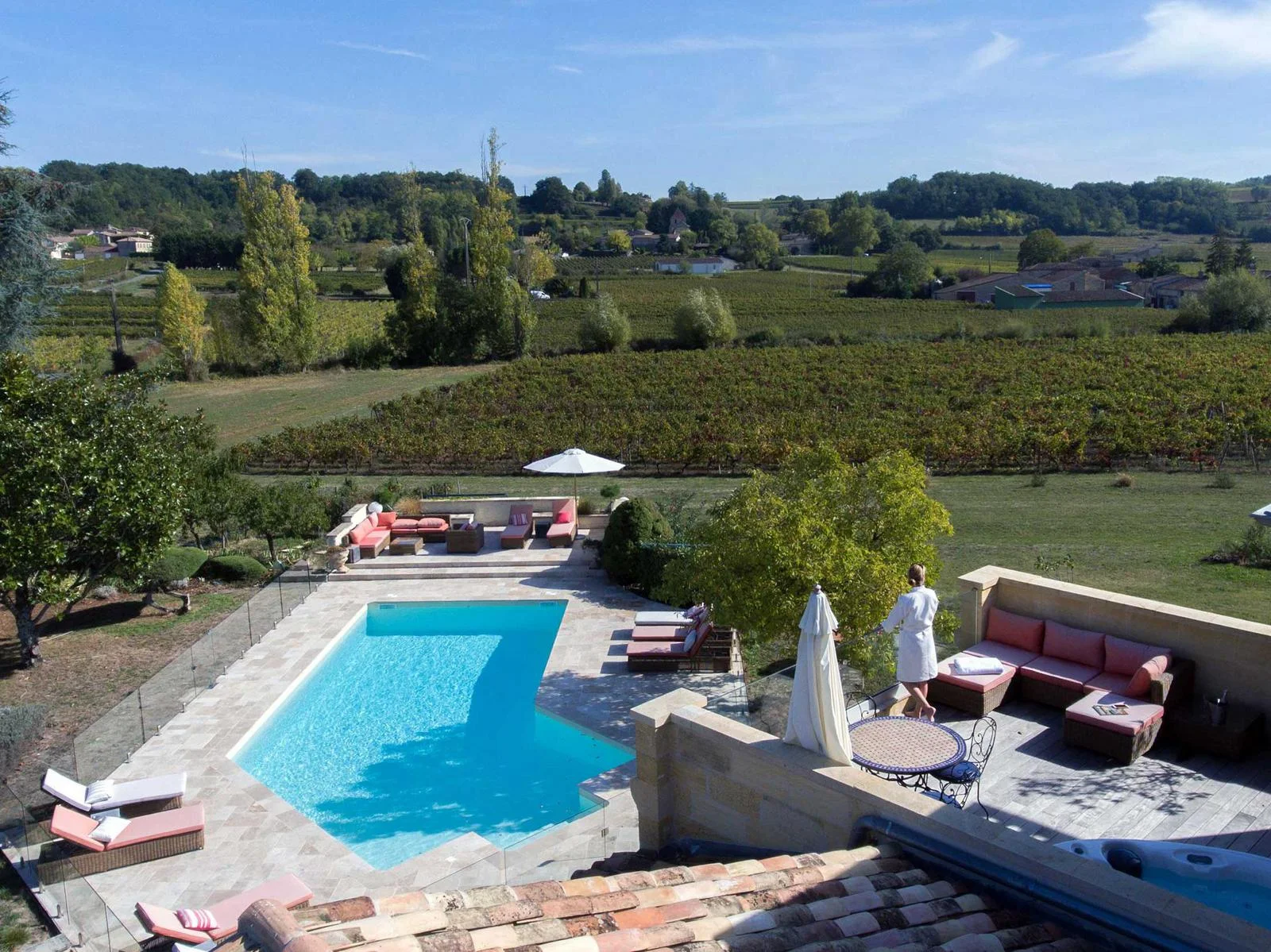 Une femme sur la terrasse face à la piscine et aux vignes du Palanquey